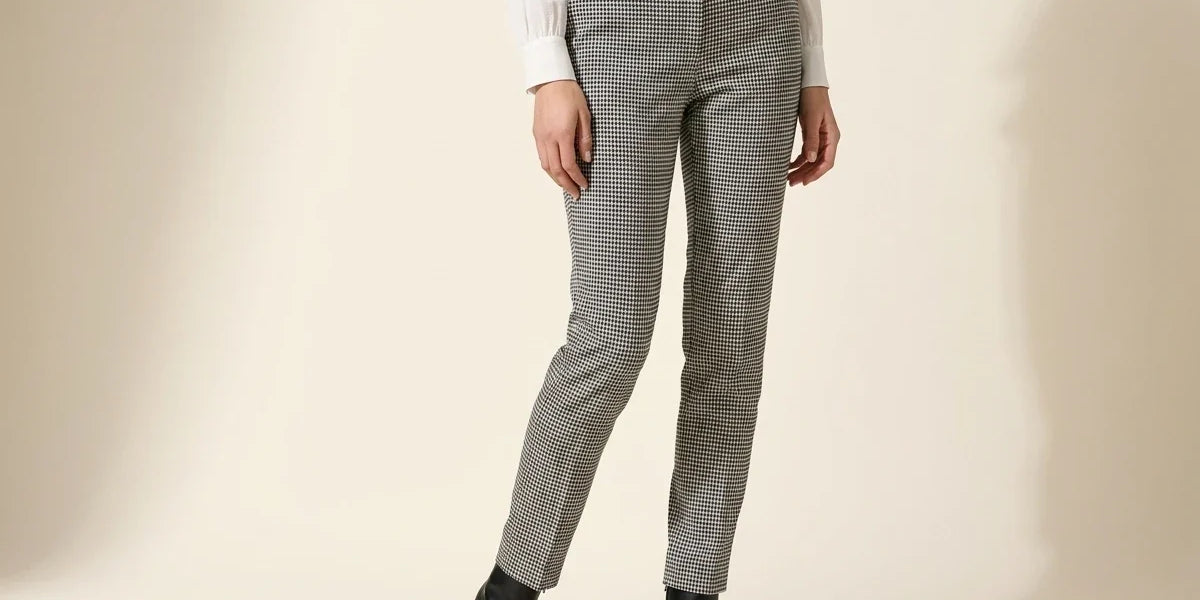 Cropped view of a woman wearing Vince Camuto black and white houndstooth skinny ankle pants, an ivory blouse, and black heeled boots.