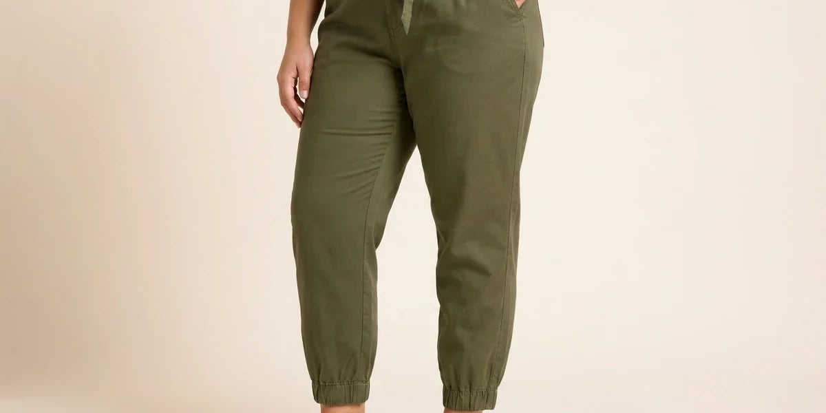 Cropped view of a woman wearing olive green tie-waist jogger pants with elastic cuffs, paired with flat white leather mules.