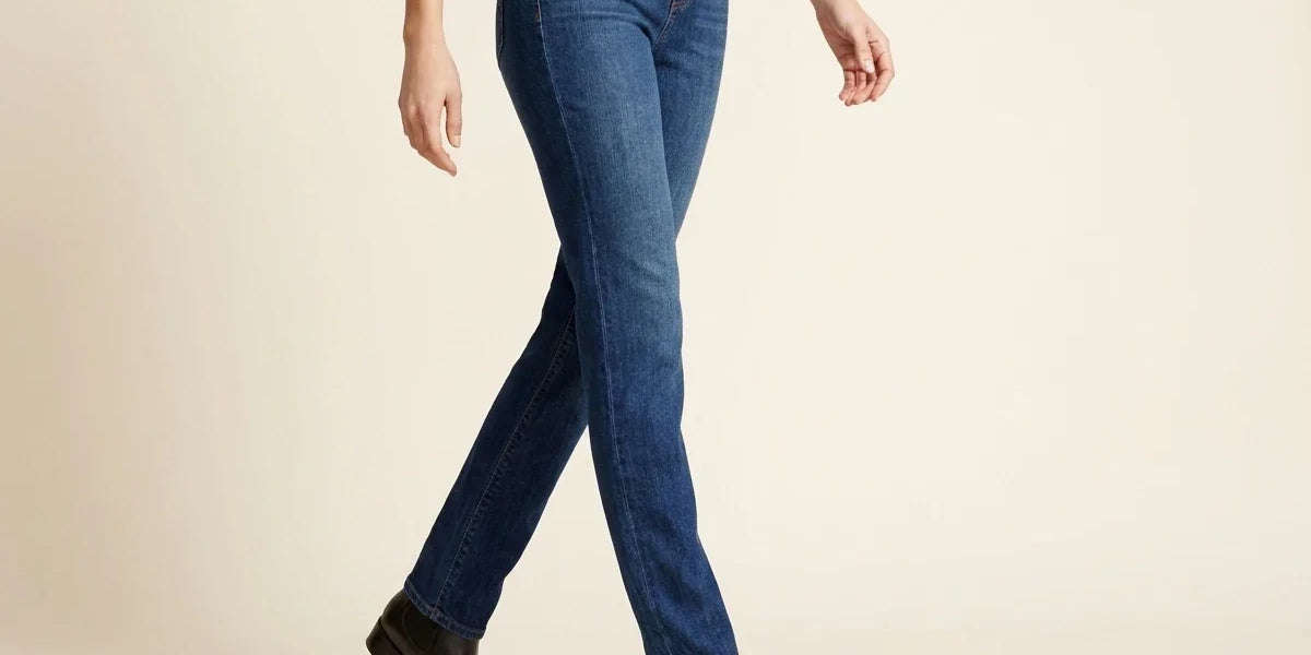 Cropped view of a woman walking in medium-wash straight-leg denim jeans paired with black leather Chelsea ankle boots and a white top.
