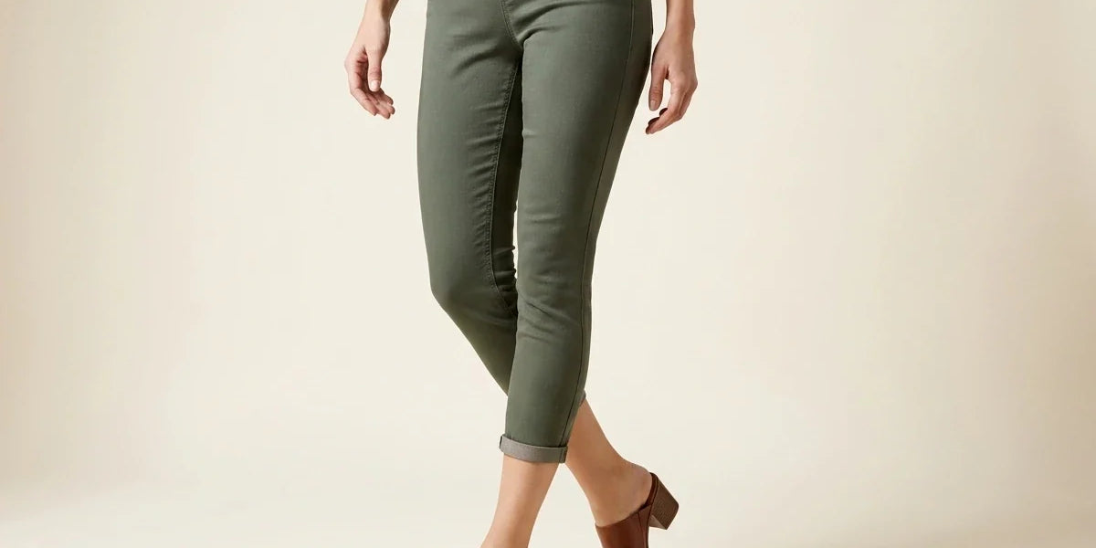 Cropped view of a woman wearing olive green stretch pull-on capri pants with cuffed hems and cognac brown leather block-heel mules.