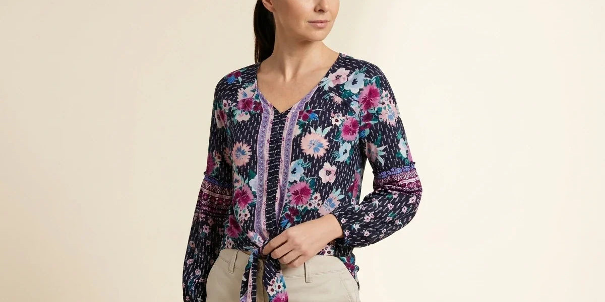 Brunette woman modeling a petite navy blue floral tie-front blouse with long balloon sleeves paired with beige chinos.