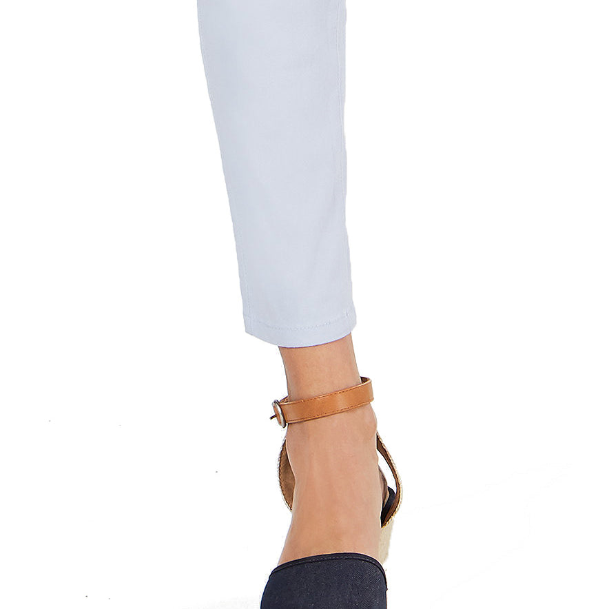 Navy wedge sandals with a tan strap worn with light blue jeans on a white background