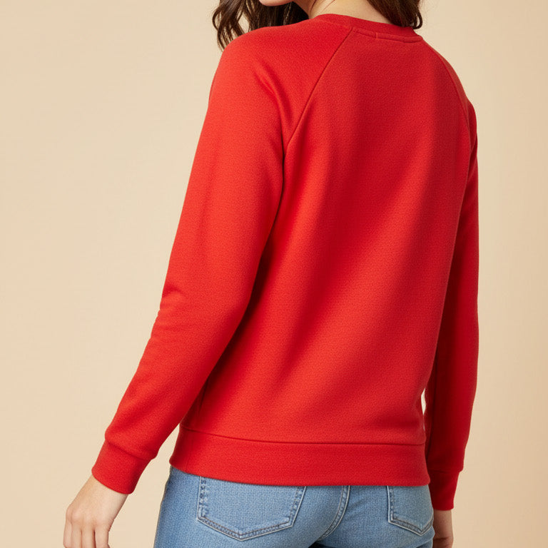 Woman wearing a red sweatshirt and blue jeans on a beige background