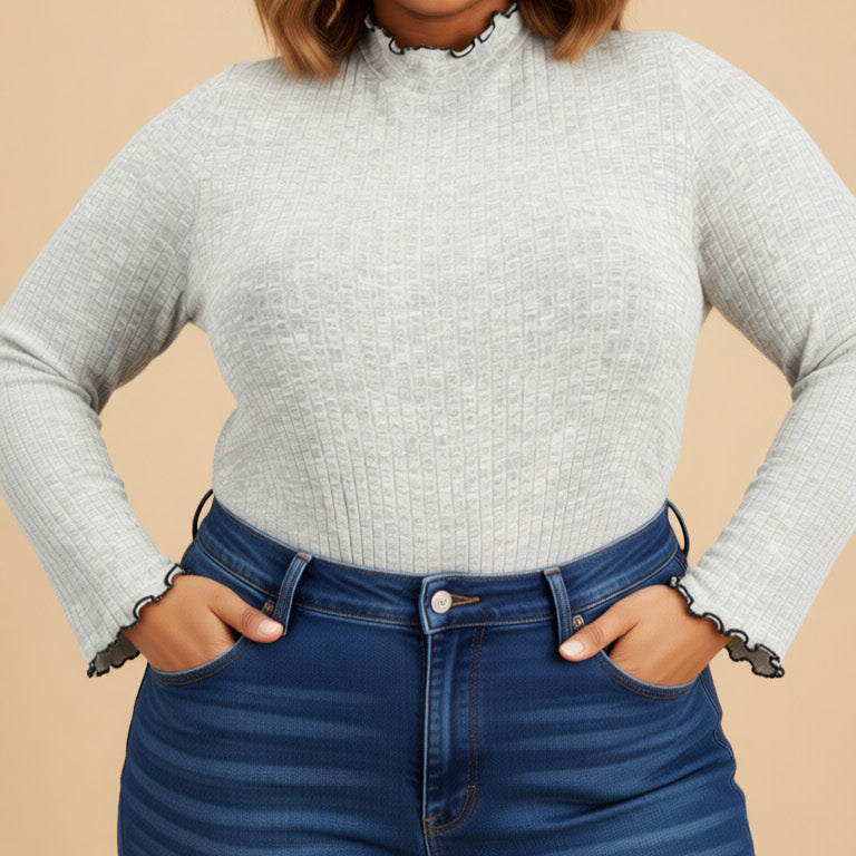 Woman wearing a gray sweater and blue jeans against a beige background