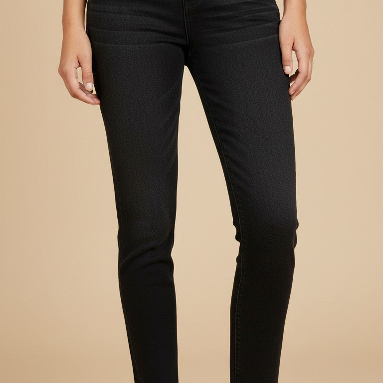 Person wearing black jeans and white sneakers on a beige background