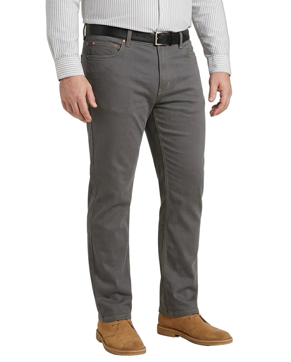 A man wearing gray slim-fit jeans with a black belt, a white striped long-sleeve shirt, and brown suede shoes, shown from the waist down on a white background.