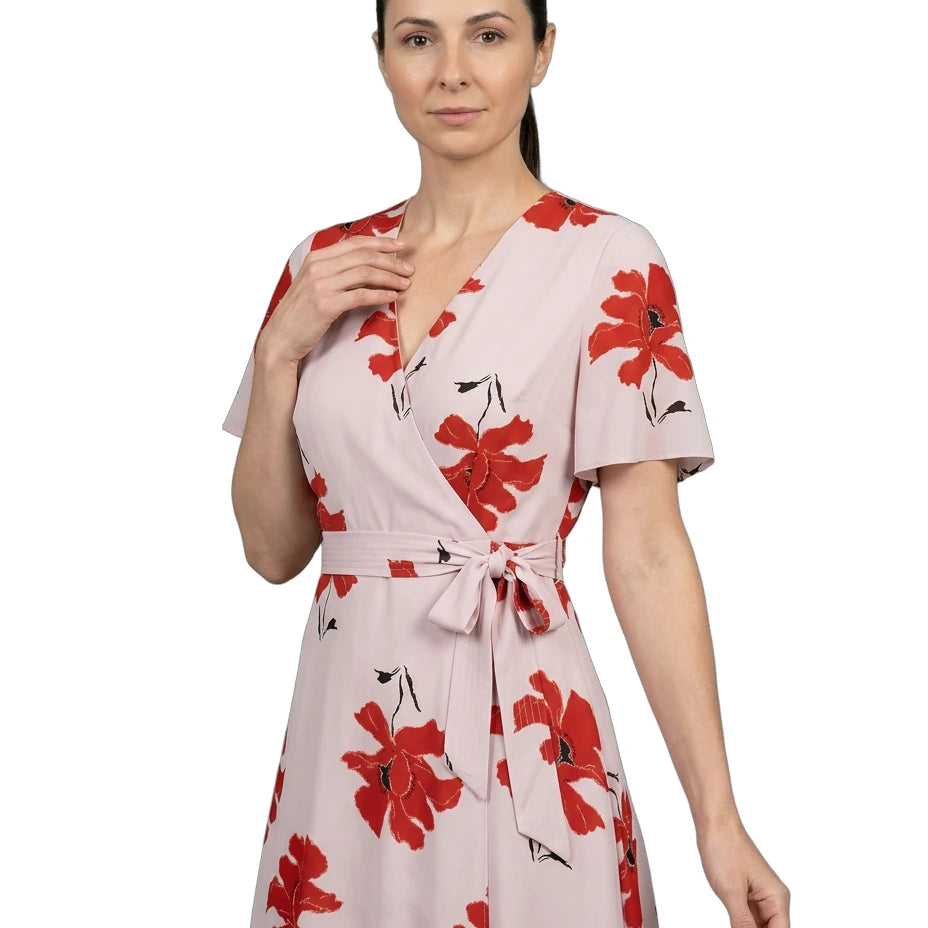 Woman wearing a pink dress with red floral patterns on a white background