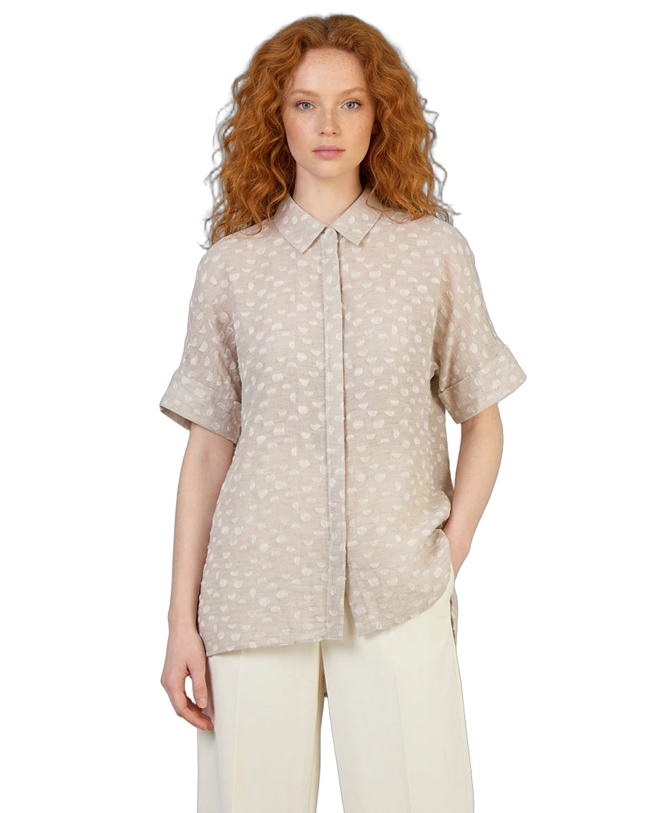 Woman wearing a beige patterned shirt on a white background