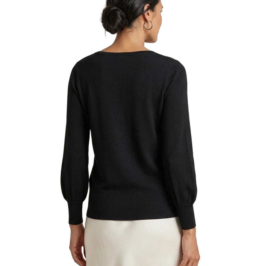 A woman shown from the back wearing a black long-sleeve knit top with balloon sleeves and a cream-colored skirt, against a plain white background.