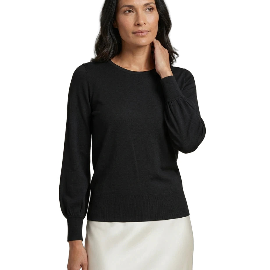 A woman modeling a black long-sleeve knit top with balloon sleeves, paired with a white skirt, against a plain white background.