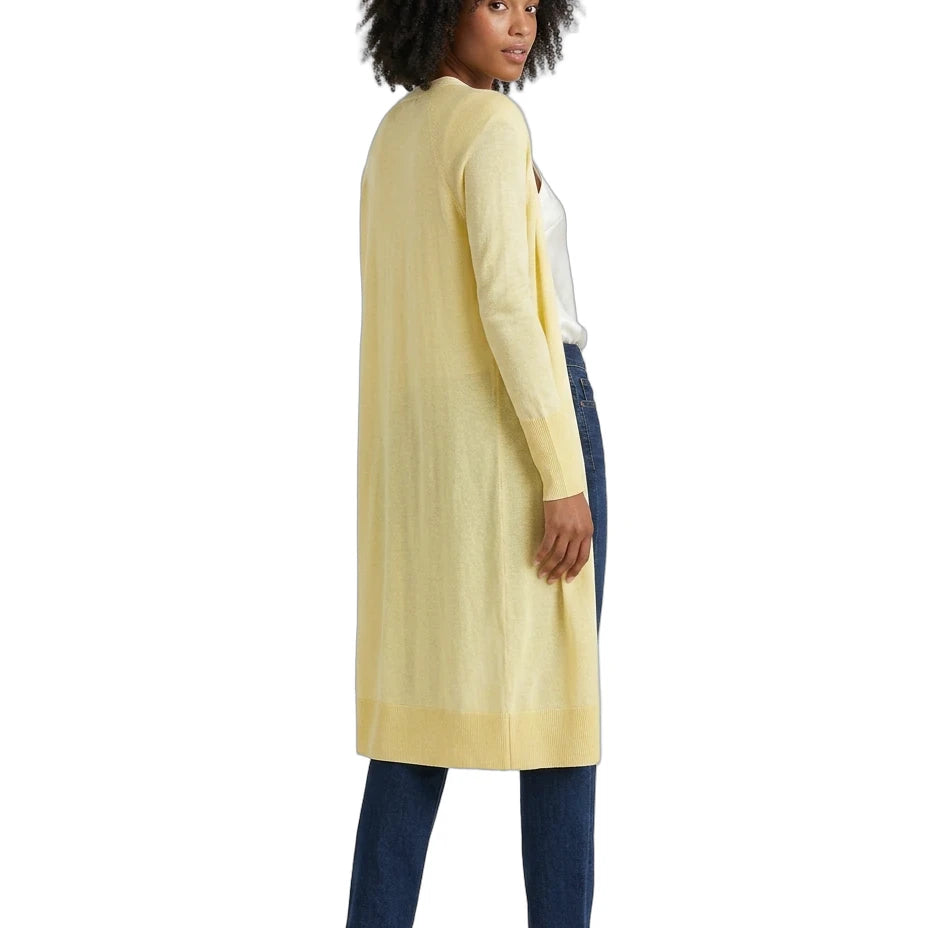 Woman wearing a long light yellow cardigan over a white top and dark pants on a white background