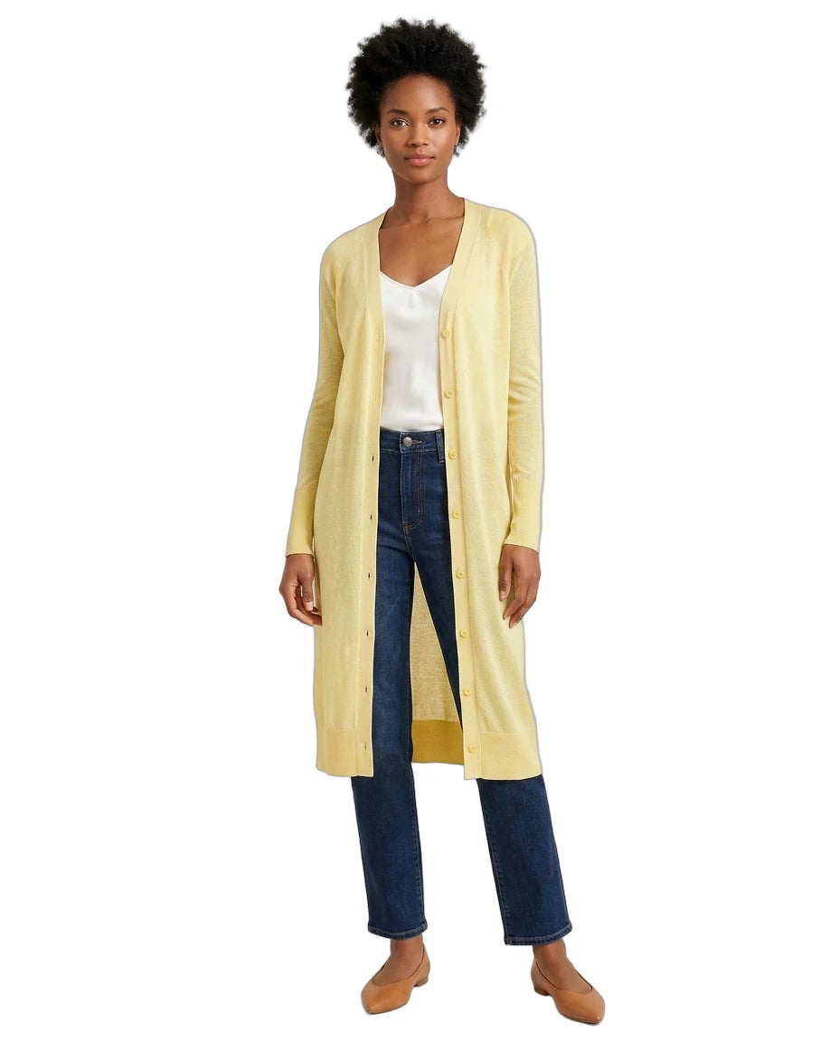 Woman wearing a long yellow cardigan over a white top and blue jeans on a white background