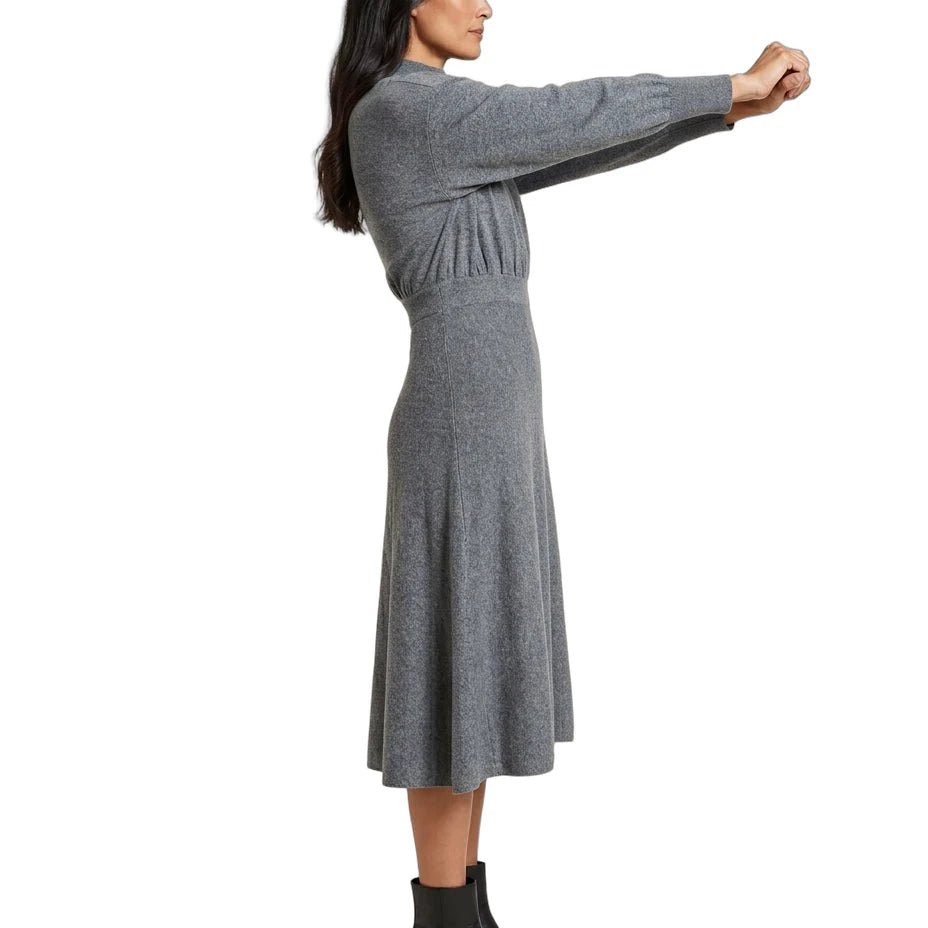 A woman modeling a gray long-sleeve knit midi dress with a gathered waist, shown in profile against a plain white background.