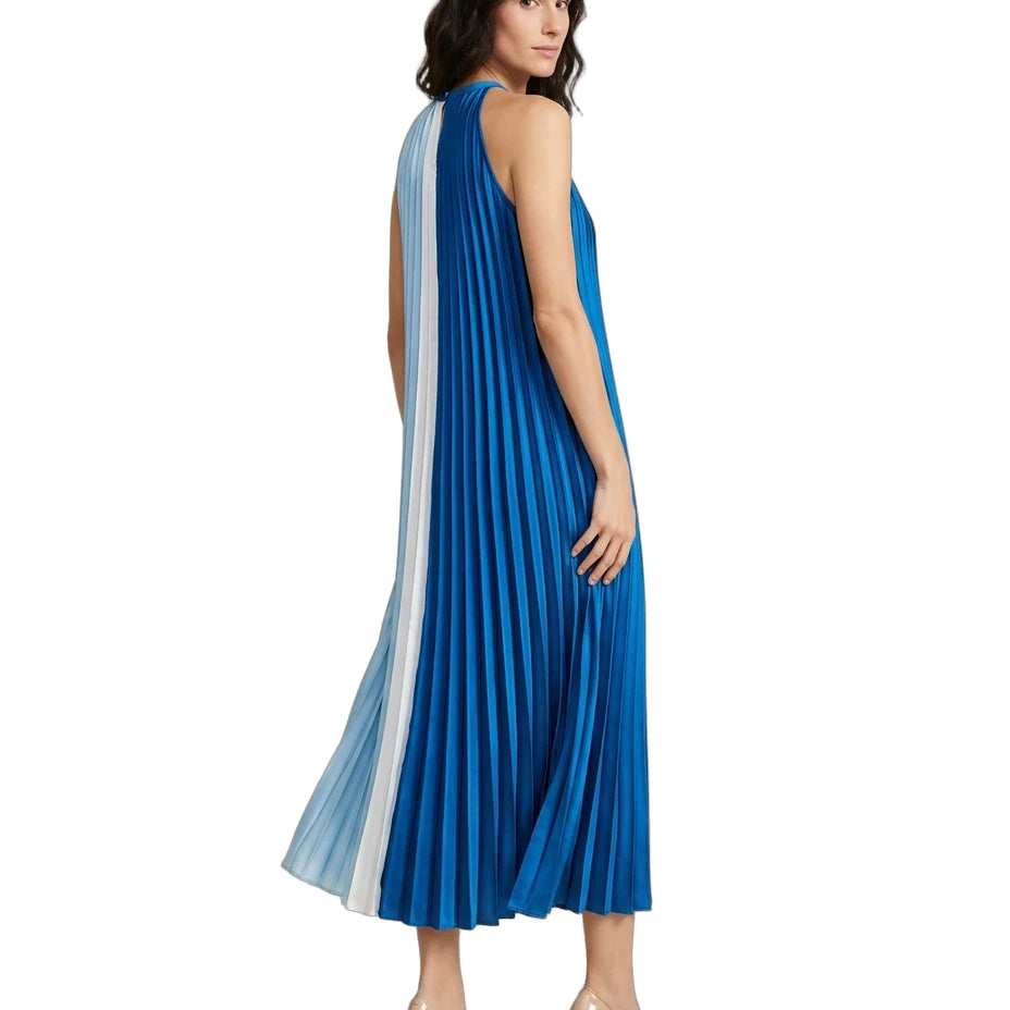 A woman modeling a sleeveless pleated midi dress with a vertical striped panel in shades of blue, white, and light blue, paired with beige high heels against a plain white background.