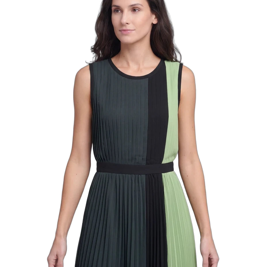 A woman modeling a sleeveless pleated dress with vertical color-blocked panels in dark charcoal gray, black, and light sage green, featuring a matching waistband.