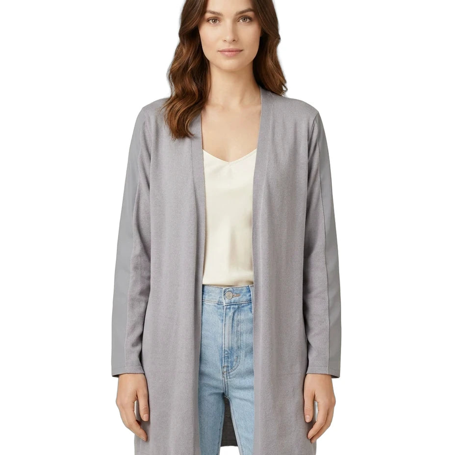 Woman wearing a gray cardigan over a white top and blue jeans on a white background