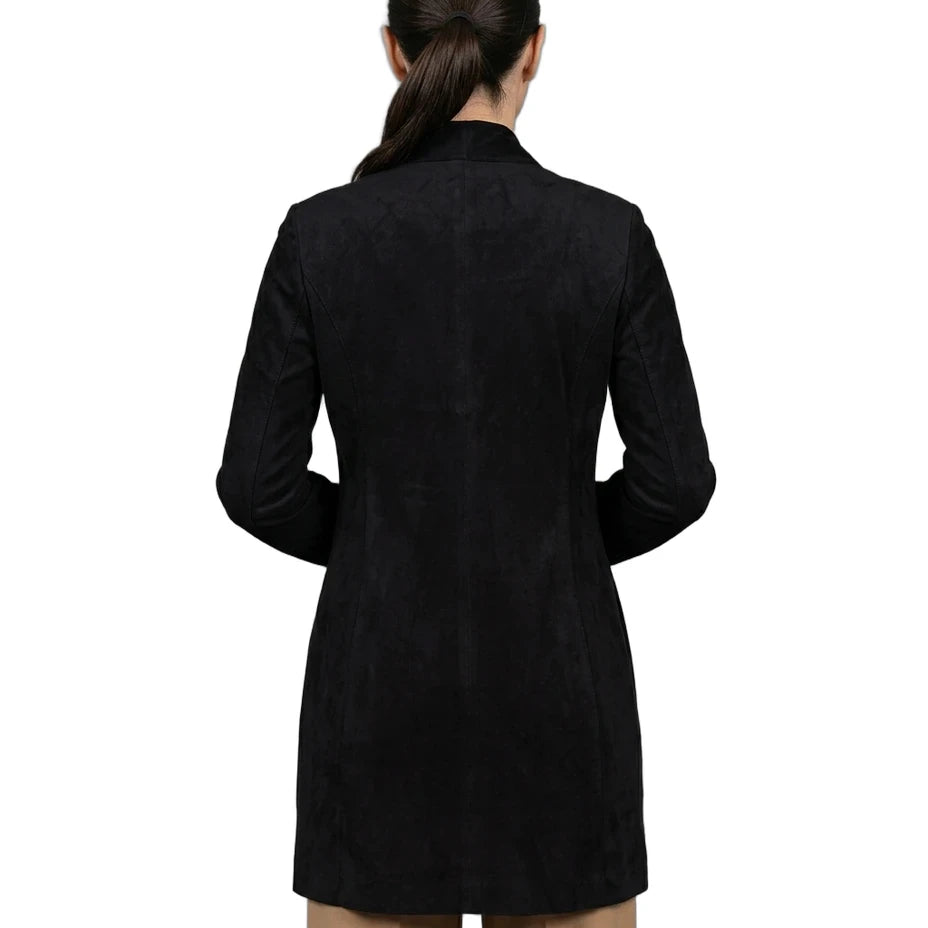 A woman viewed from the back wearing a black long-sleeve blazer or coat over tan pants, photographed against a plain white studio background.