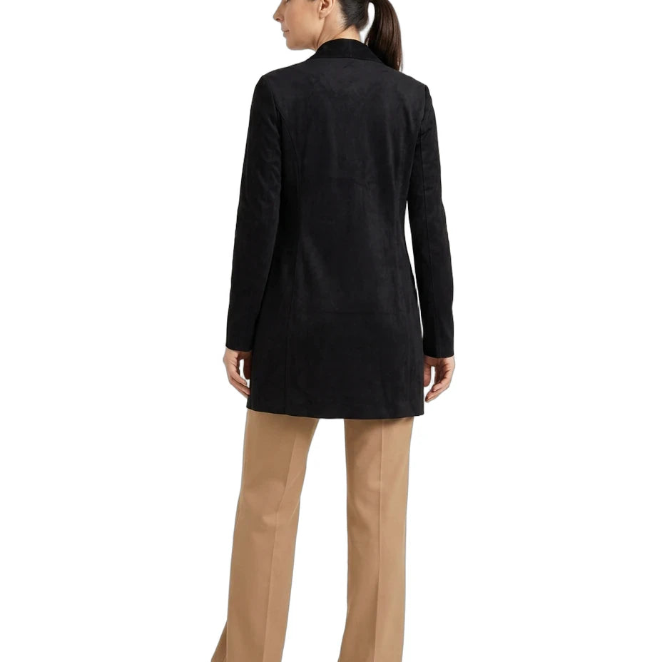 A woman shown from the back wearing a black longline blazer, tan wide-leg trousers, and white sneakers against a plain white background.