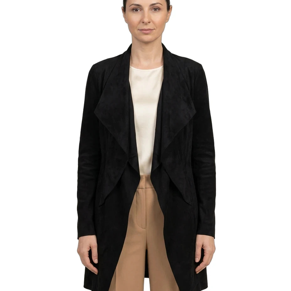 A woman modeling a black open-front wrap-style coat over a cream top and beige trousers, photographed against a plain white studio background.