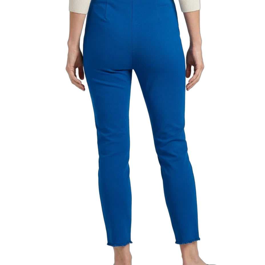 A person shown from the back wearing bright royal blue cropped pants, a cream long-sleeve top, and black flats against a plain white studio background.
