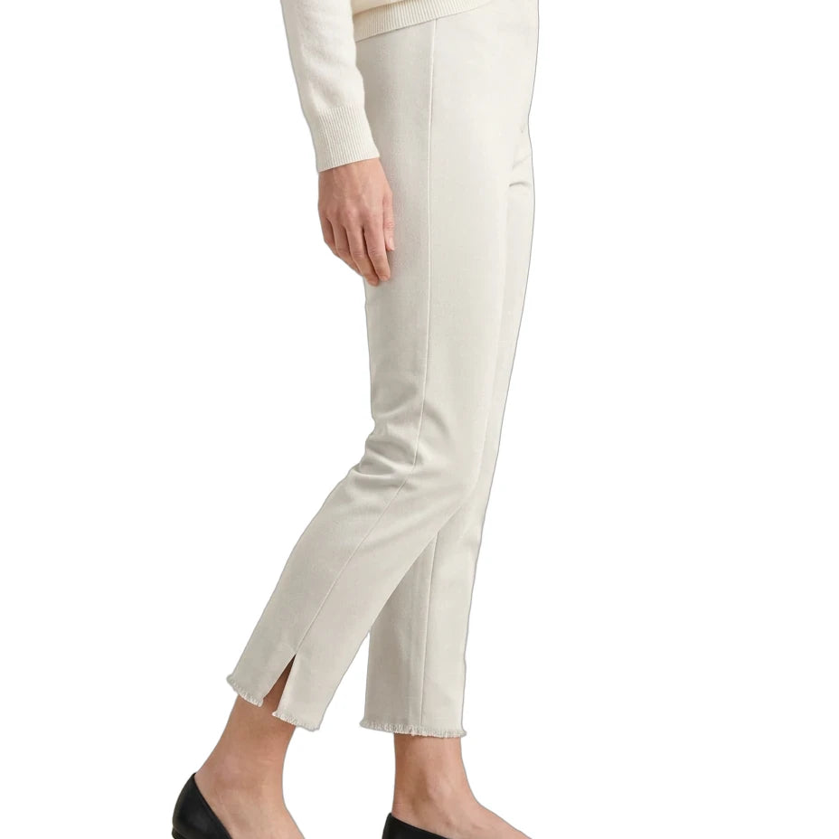 A side-profile view of a person wearing off-white cropped trousers with side slits at the ankles, paired with black flats and a cream sweater, against a plain white background.