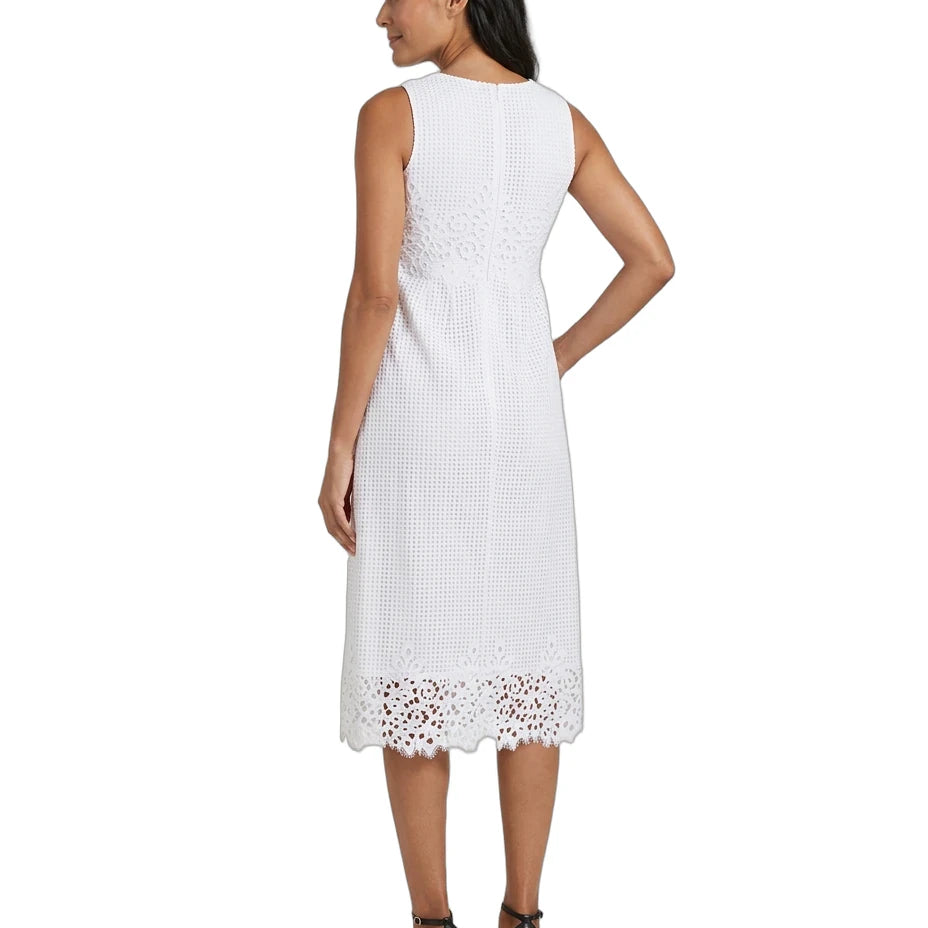 A woman shown from the back wearing a sleeveless white midi dress with a textured woven pattern and eyelet lace trim at the hem, paired with black high-heeled sandals against a plain white background.