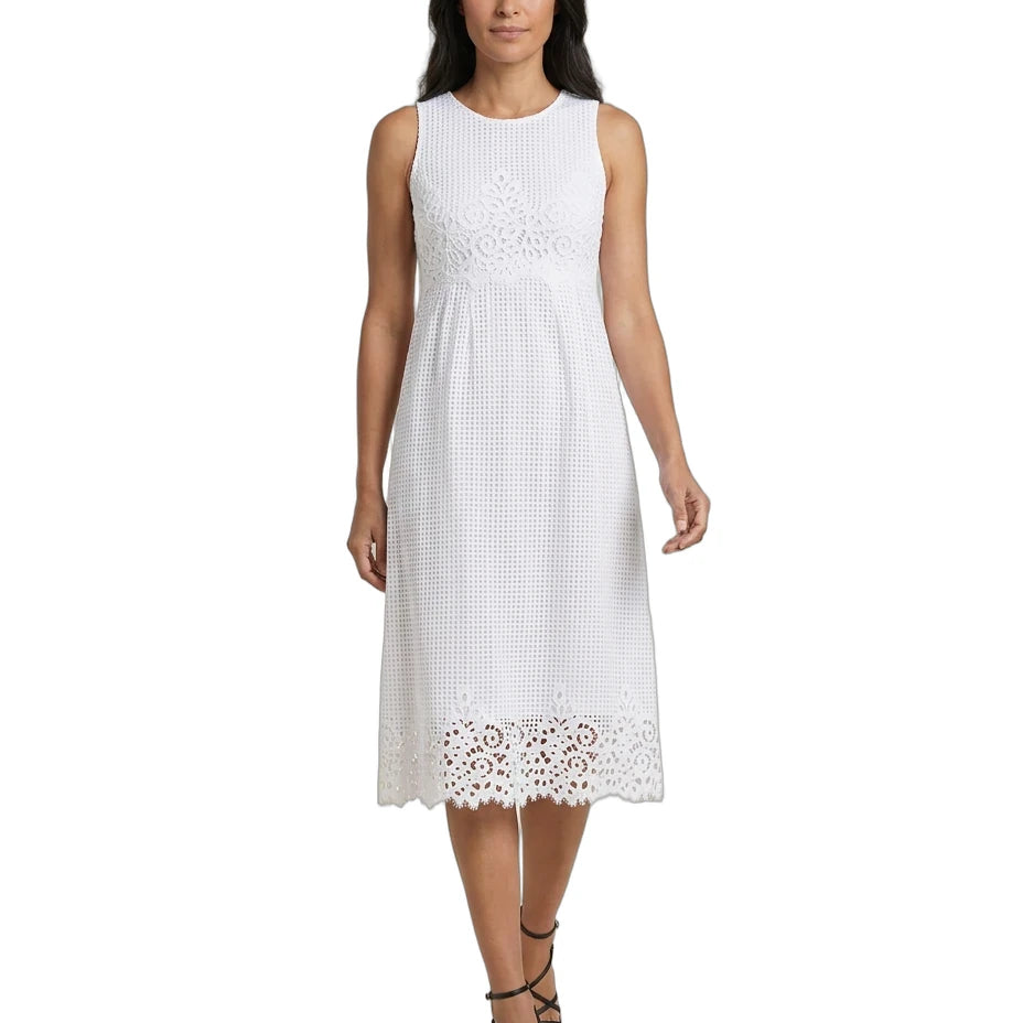 A woman modeling a sleeveless white midi dress with a textured eyelet pattern and lace trim at the hem, paired with black strappy high-heeled sandals against a plain white background.
