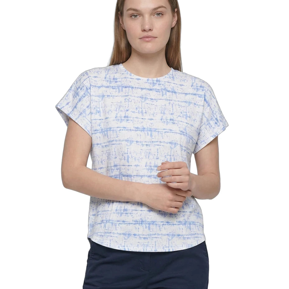 A woman modeling a short-sleeve crewneck top with a blue and white abstract textured pattern, paired with navy pants, against a plain white background.