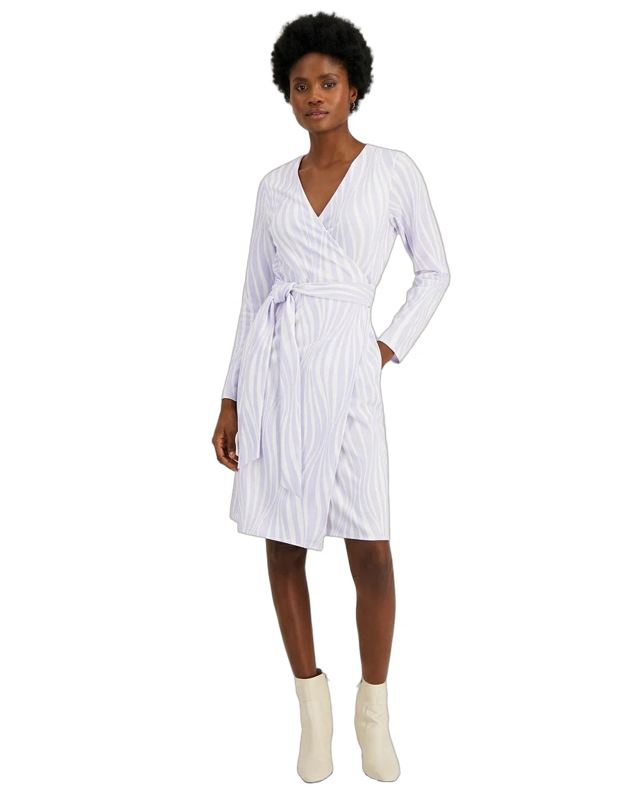 A woman modeling a white wrap dress with thin vertical blue stripes, featuring a V-neck, long sleeves, and a self-tie belt, paired with off-white ankle boots against a plain white background.