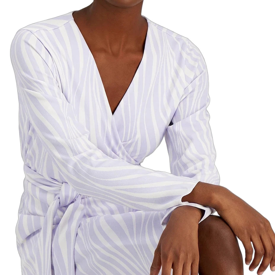 A woman wearing a white wrap-style long-sleeve dress with a light lavender-purple zebra-like stripe pattern, shown from the chest down against a plain white background.
