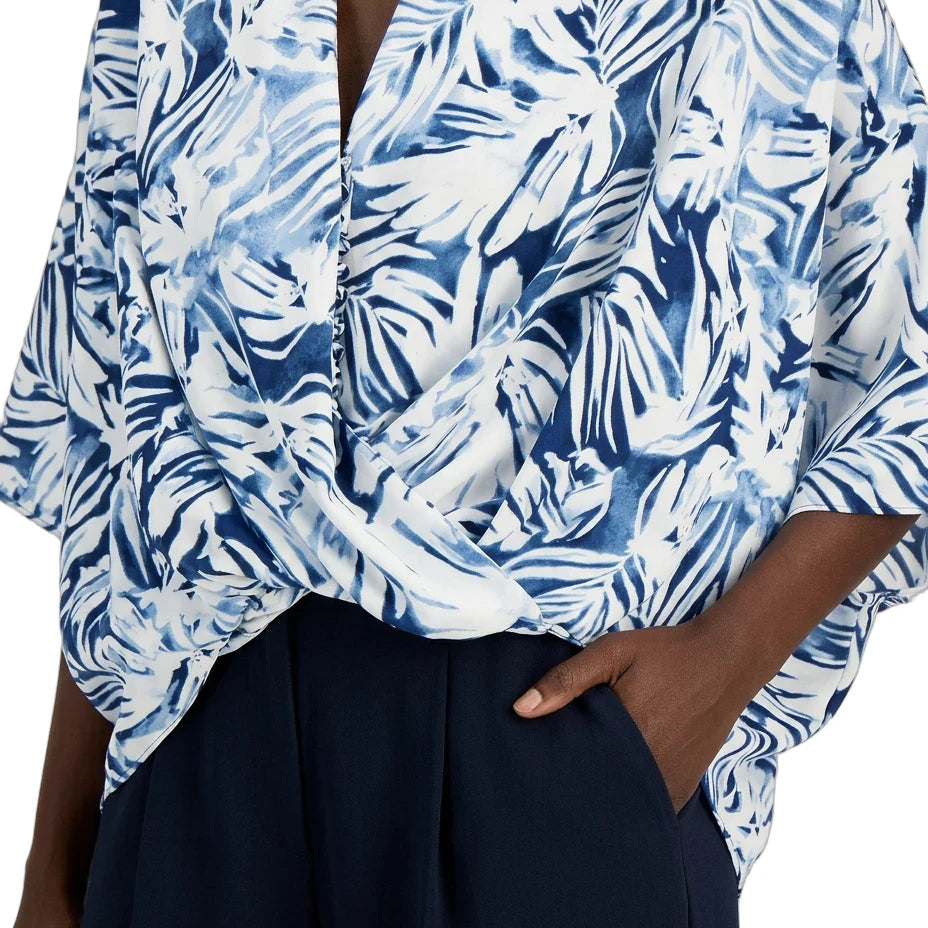 Blue and white patterned top worn by a person with a dark background