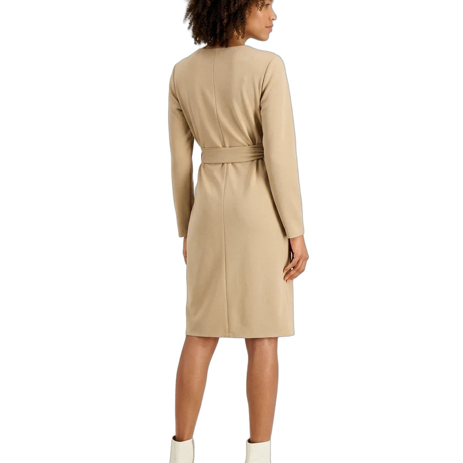 A woman shown from the back wearing a beige long-sleeve knee-length dress with a matching waist tie, paired with white ankle boots, against a plain white background.