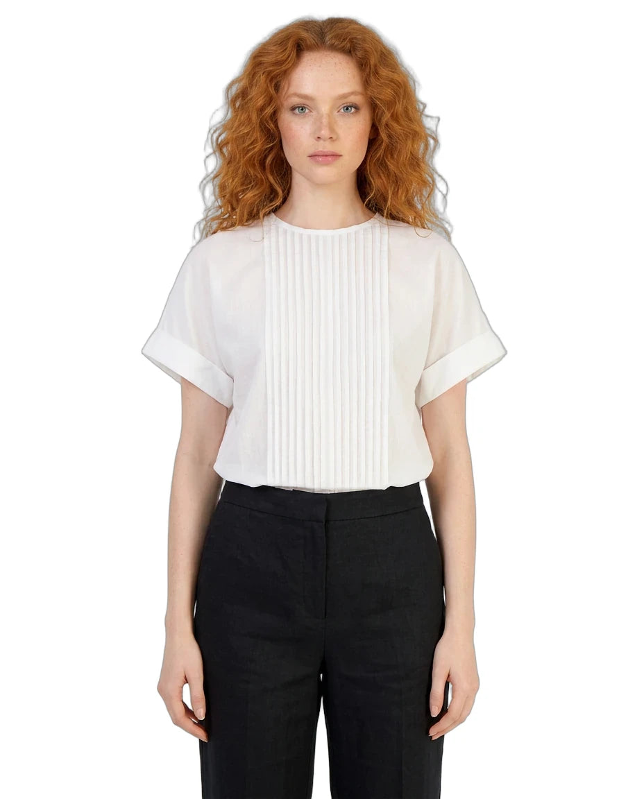 Woman wearing a white blouse with ruffled sleeves and black pants on a white background