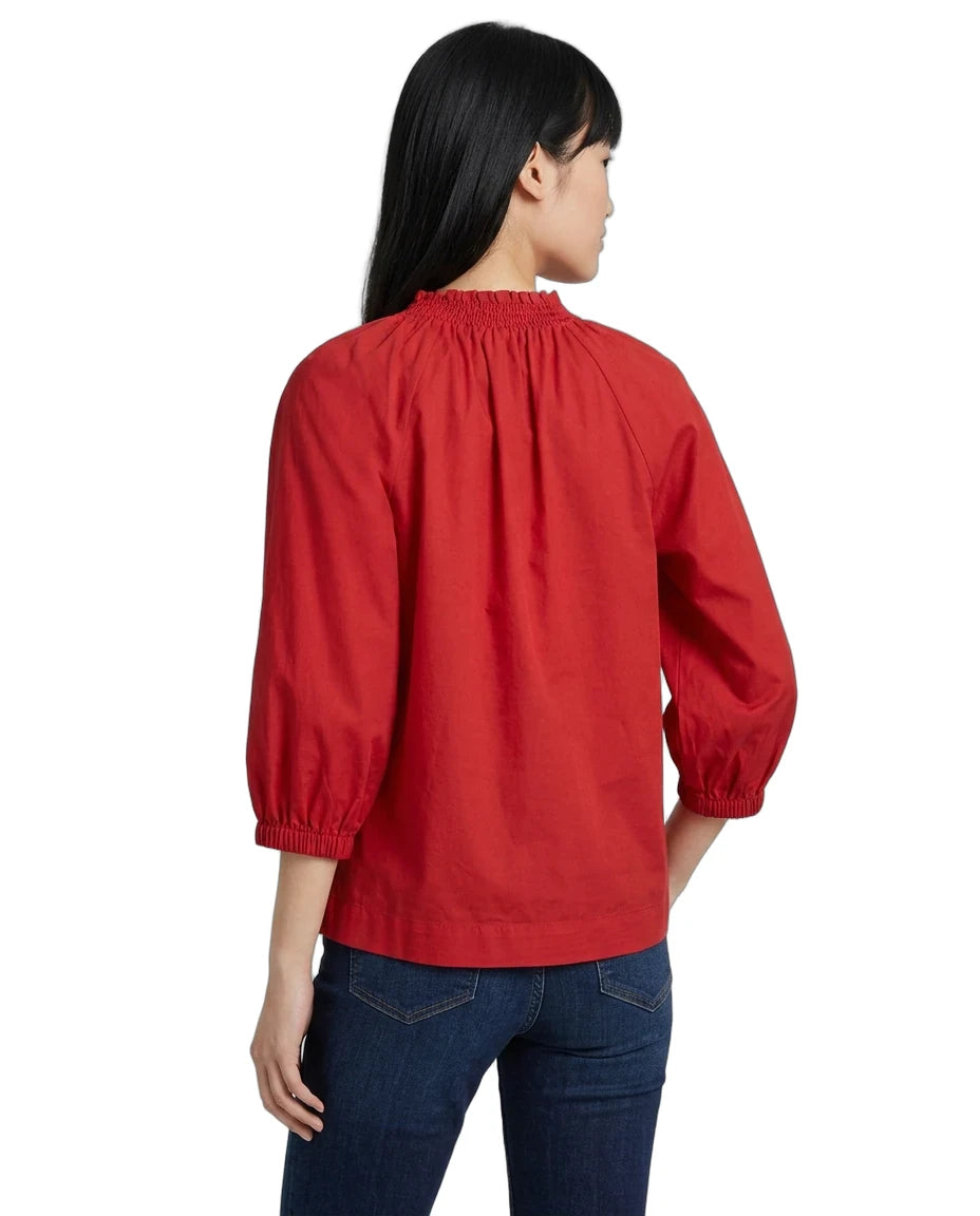 A woman shown from the back wearing a bright red long-sleeve blouse with a gathered elastic neckline and elastic cuffs, paired with dark blue jeans, against a plain white background.