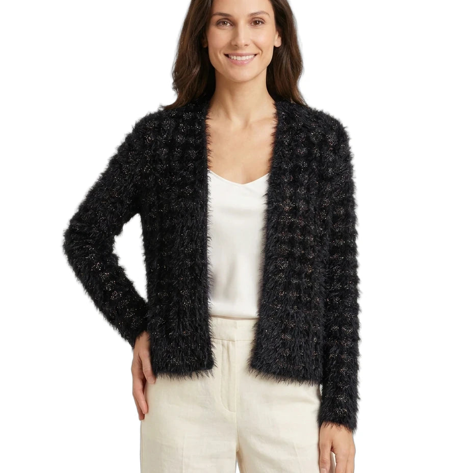 Woman wearing a black fuzzy cardigan over a white top and beige pants on a white background