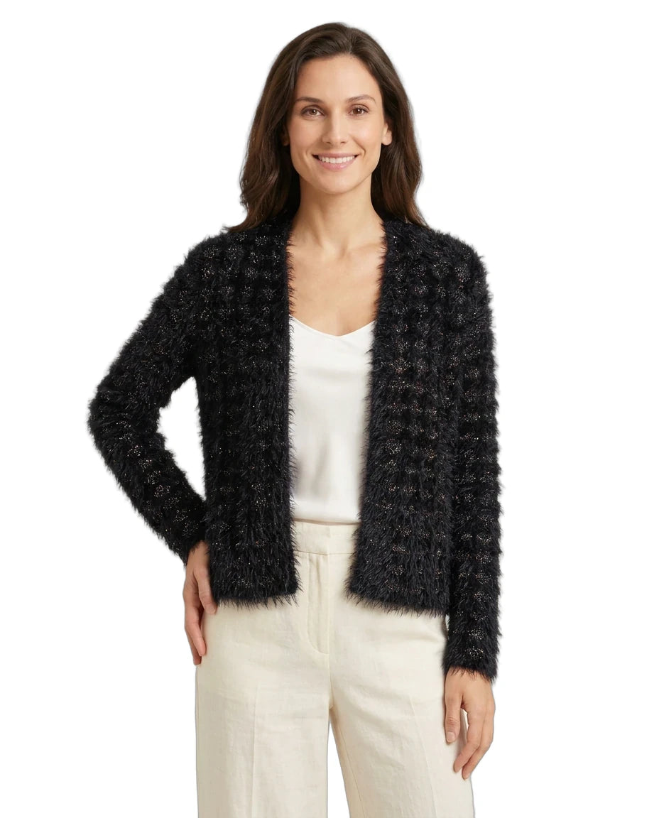 Woman wearing a black fuzzy cardigan over a white top and beige pants on a white background