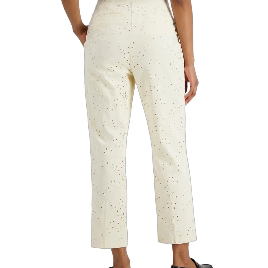 A person shown from the back wearing cream-colored cropped trousers with a subtle speckled pattern, paired with a navy top and black loafers, against a plain white background.