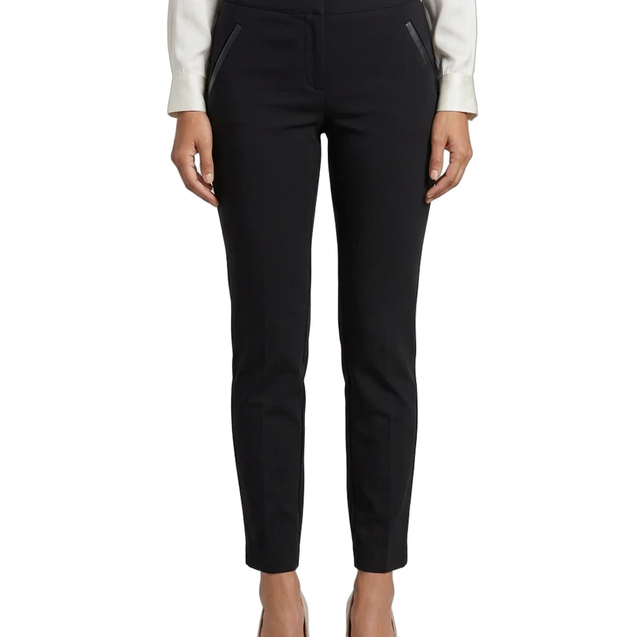 A model from the waist down wearing slim black trousers with diagonal zippered pockets, styled with a white blouse and beige heels against a plain white background.