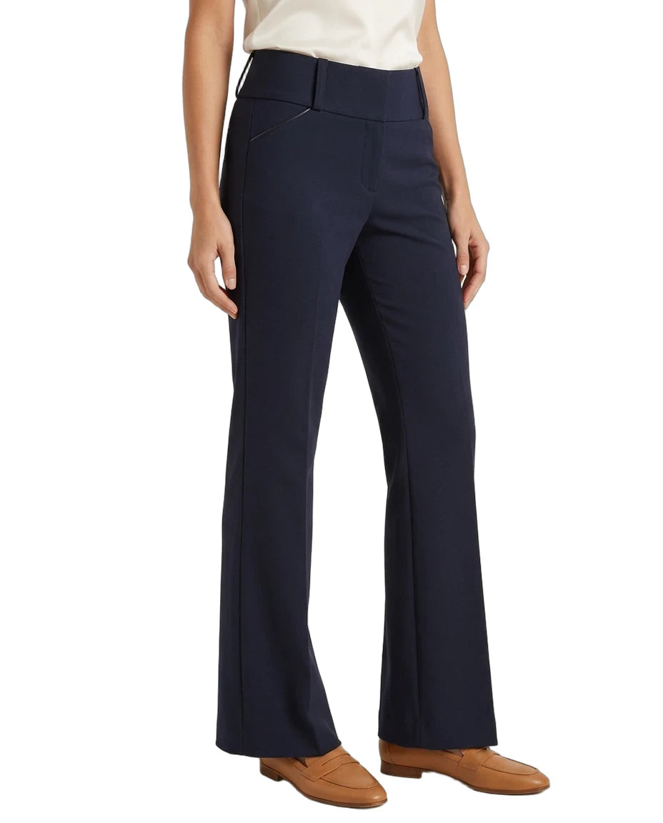 A model wearing a pair of dark navy blue high-waisted flared trousers, paired with a cream top and tan loafers, shown against a plain white background.