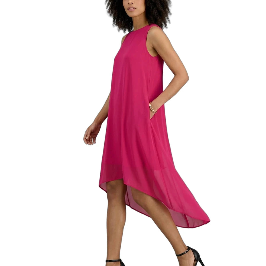 A woman modeling a sleeveless, high-low magenta dress with side pockets, paired with black strappy high-heeled sandals, against a plain white background.