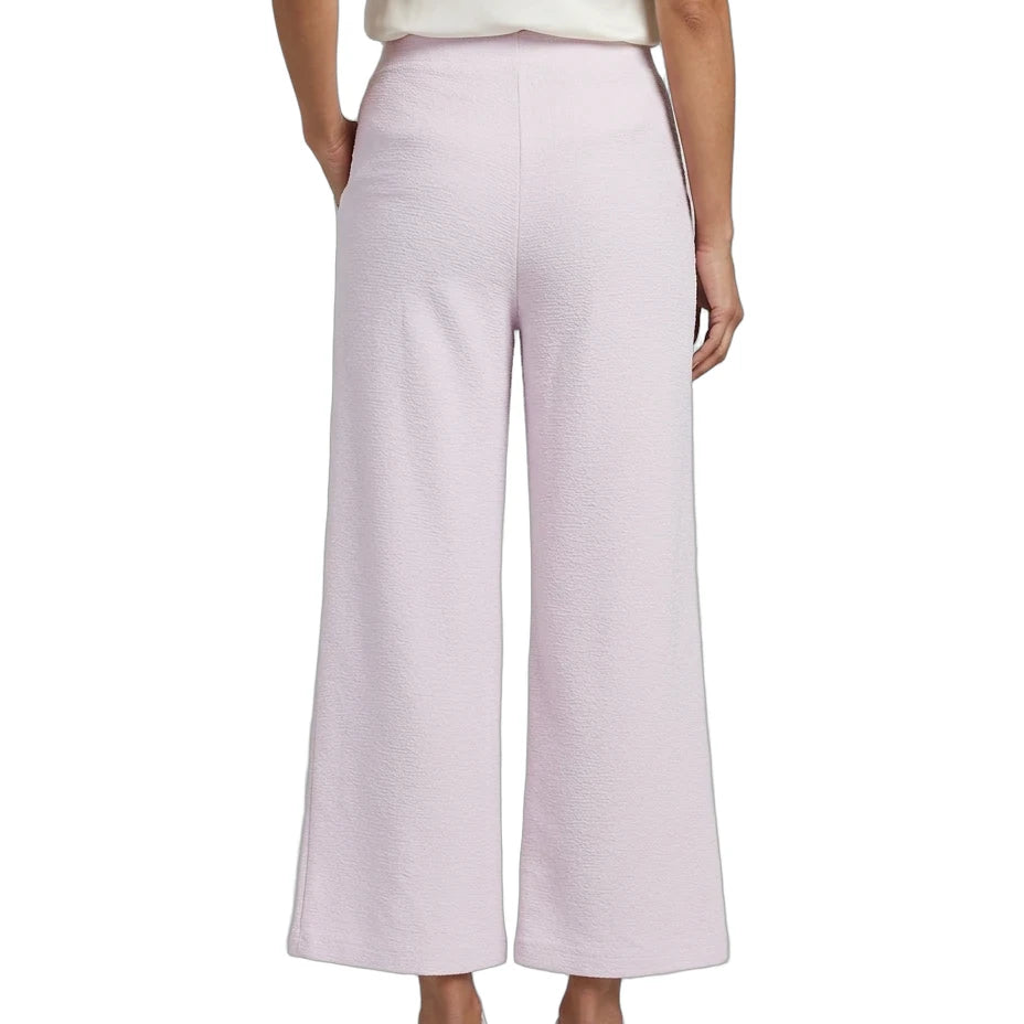 A model shown from the back wearing light pink wide-leg cropped pants, a cream top, and white sneakers against a plain white background.