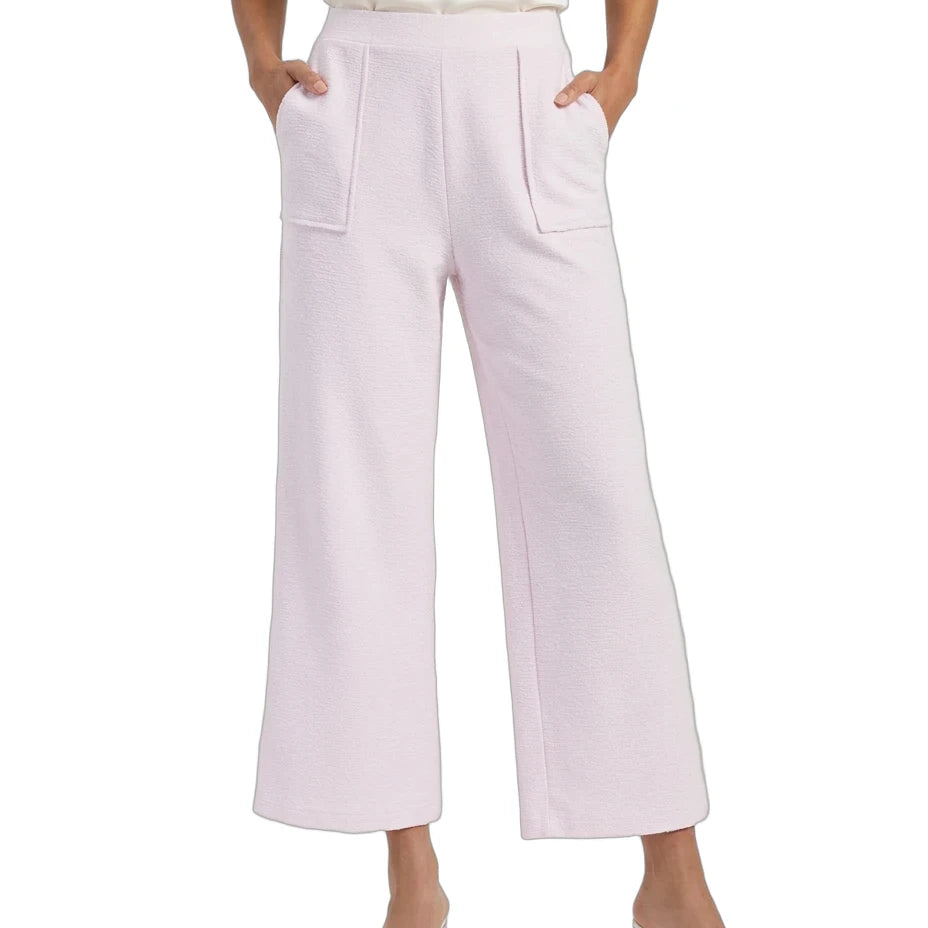 A model wearing light pink wide-leg cropped pants with front patch pockets, paired with a cream satin top and clear heeled sandals, shown against a plain white background.