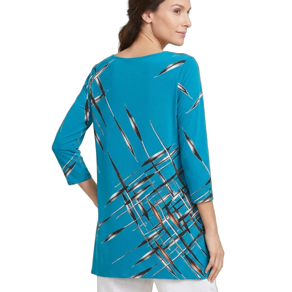A woman shown from the back wearing a turquoise blue tunic top with a black, white, and gray brushstroke pattern, paired with white pants, against a plain white background.