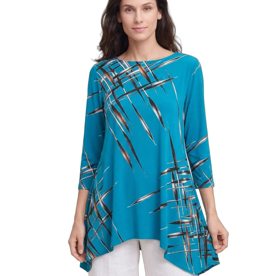 A woman modeling a turquoise blue three-quarter sleeve tunic top with a black, white, and brown abstract brushstroke pattern, paired with white pants, against a plain white background.