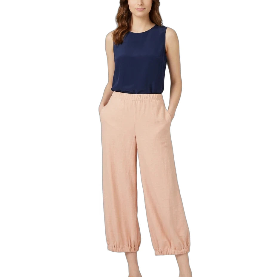 A woman modeling a sleeveless navy blue top and light peach wide-leg cropped pants with elastic cuffs, paired with tan heeled sandals, against a plain white background.