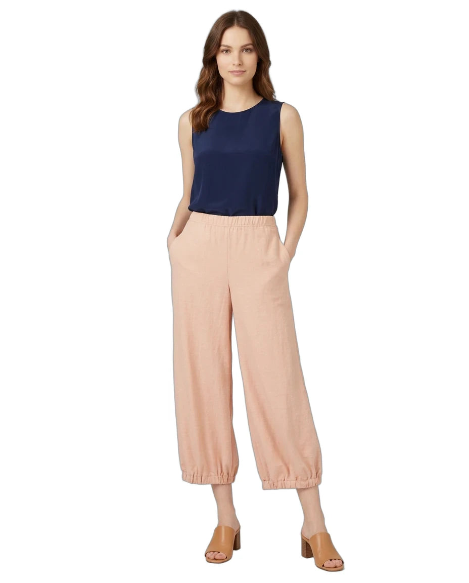 A woman modeling a sleeveless navy blue top and light peach wide-leg cropped pants with elastic cuffs, paired with tan heeled sandals, against a plain white background.