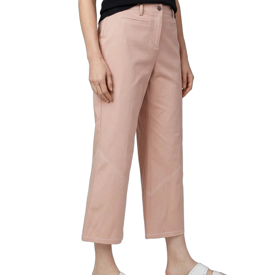 A model wearing dusty pink cropped pants, a black t-shirt, and white slide sandals, shown from the waist down against a plain white background.
