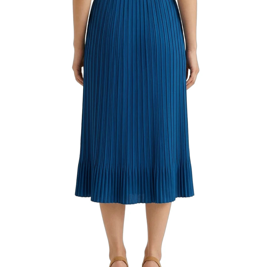 A model from the back wearing a vibrant blue pleated midi skirt, paired with a white top and tan high-heeled sandals, set against a plain white background.