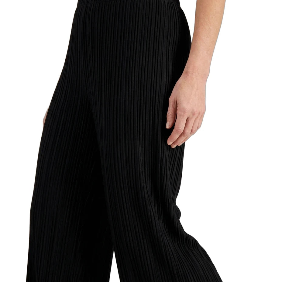 Black pleated wide-leg trousers shown on a model from the waist down, paired with a cream satin top against a plain white background.