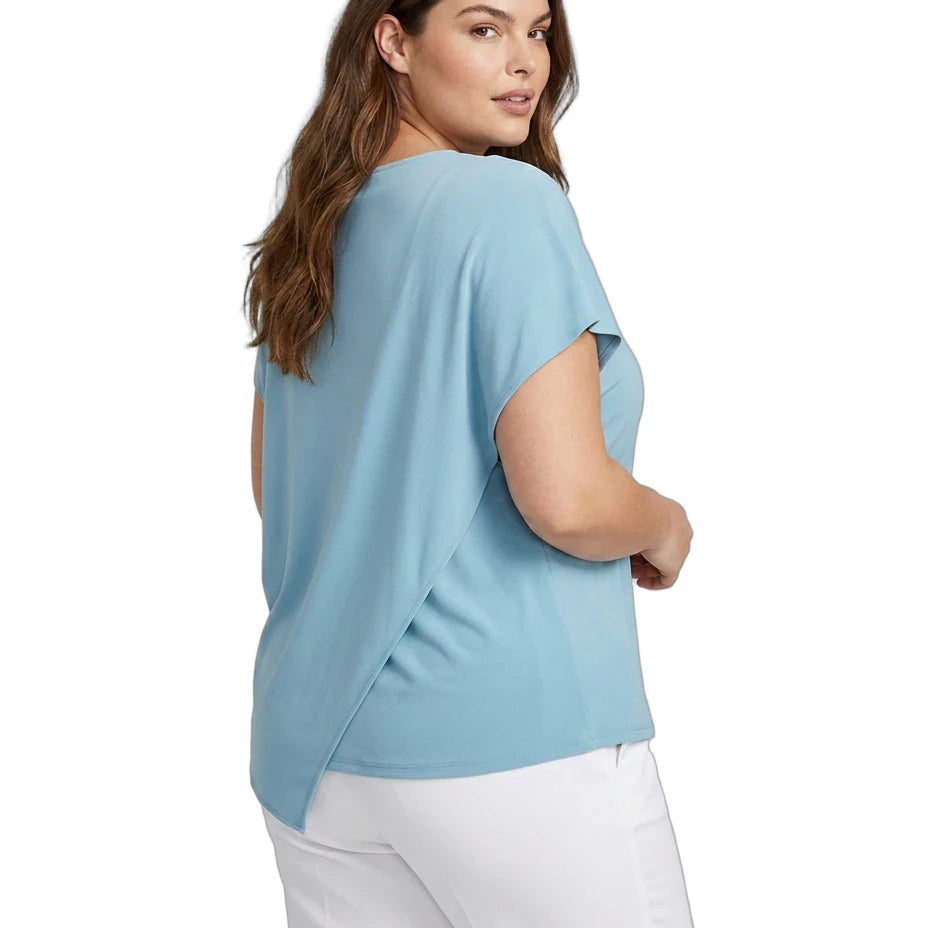 Woman wearing a light blue top and white pants on a white background